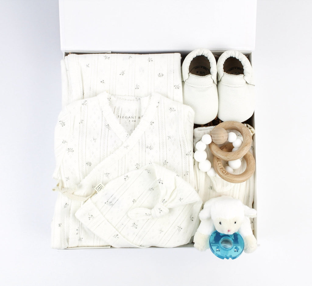 A baby gift box filled with all white essentials for baby. Box includes outfit, blanket, shoes, teether and lamb pacifier.