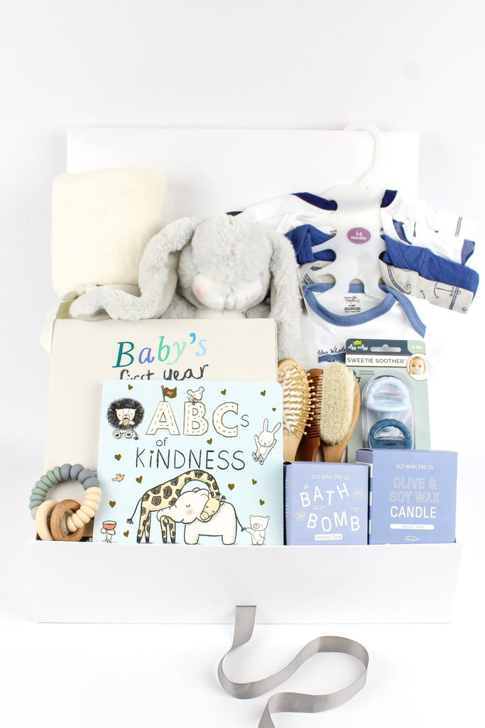 A baby boy gift featuring a stuffed bunny, blanket, bodysuits, books, teether and items for the new parents.