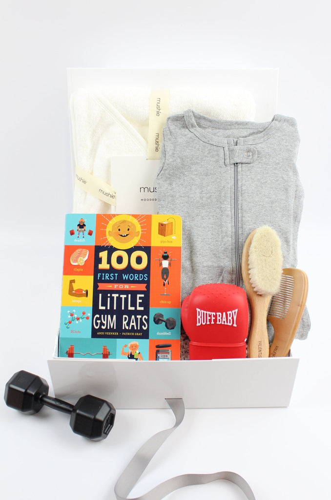 Baby gift basket with books, toys, and baby clothes on a white background